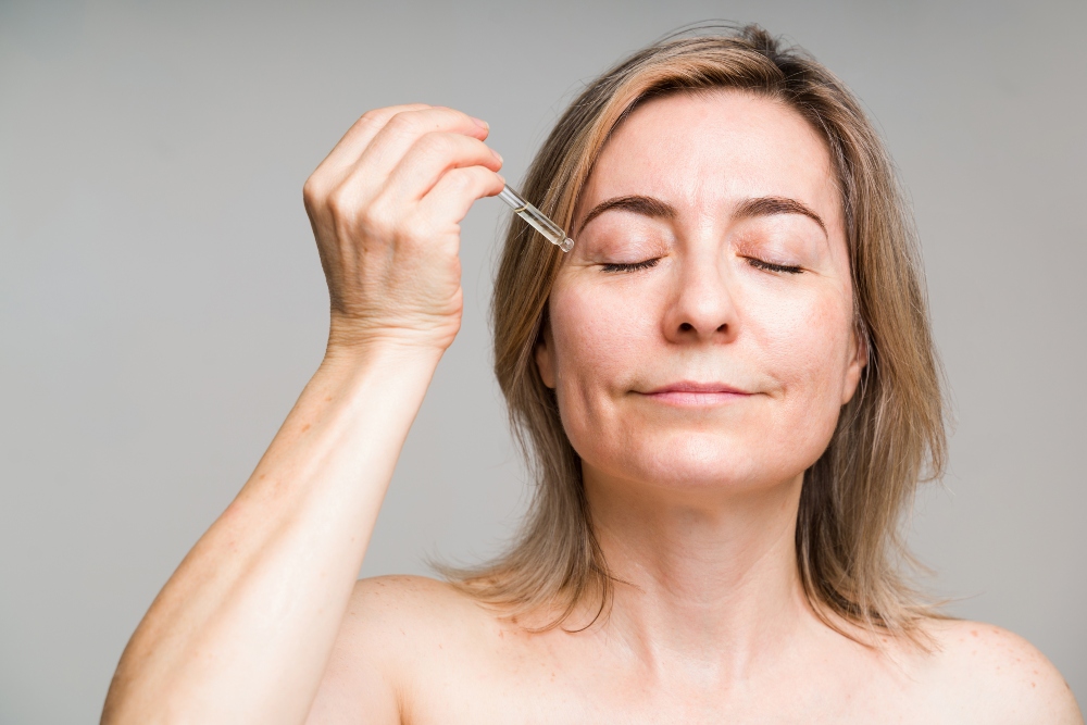 Die Haut reagiert sensibel auf äußere Einflüsse und profitiert deshalb besonders von sorgfältig formulierten, hochwertigen Pflegeprodukten Frau appliziert Serum im Gesicht - Anti Aging